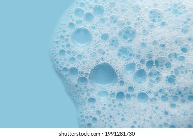 White Cosmetics Foam Texture On Blue Background. Cleanser, Shampoo Bubbles, Wash - Liquid Soap, Shower Gel, Shampoo. Texture Of White Foam On Rose Background. Cosmetics Banner With Copy Space.