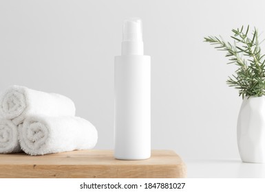 White Cosmetics Lotion Bottle Mockup With Towels And A Rosemary On A Wooden Table.