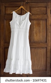 White Cotton Dress On Wooden Hanger On Antique Wardrobe