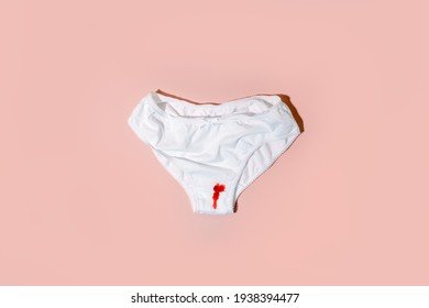 White cotton panties for women with traces of fresh red blood. Concept of menstruation, female shame, taboo, daily hygiene, critical days, premenstrual syndrome