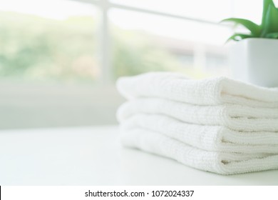 White Cotton Towels On White Counter Table Inside A Bright Bathroom Background. For Product Display Montage.