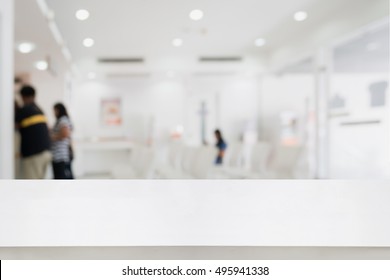 White Counter With Blur Abstract Hospital Or Bank Interior Background With Customer Or Patient At Cashier. For Product Display