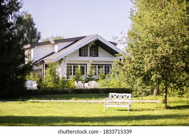 White Country House In Chalet Style. Lawn, Trees, Sunny Day.