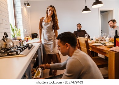 White Couple Cooking Turkey For Thanksgiving Dinner With Their Friends At Home