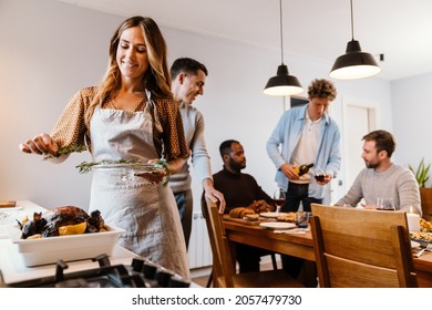 White couple cooking turkey for thanksgiving dinner with their friends at home - Shutterstock ID 2057479730