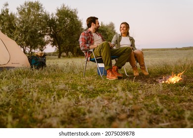 White couple smiling and sitting on chair during camping together on summer day - Powered by Shutterstock