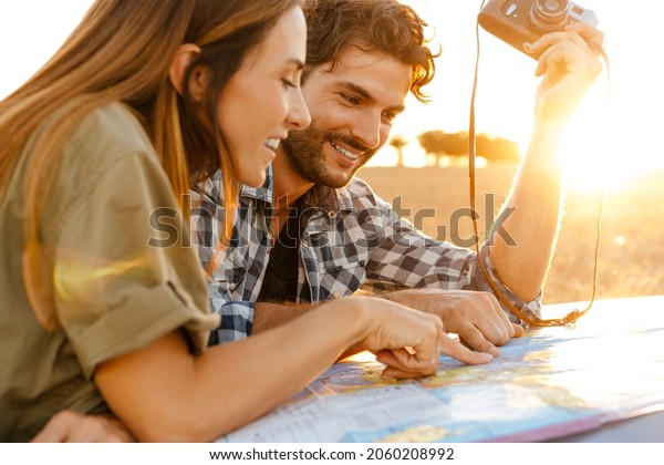 White couple smiling while examining map during\
travel on car outdoors