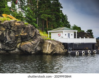 White Cozy Wooden House With Pier For Boat On A Oslofjord Rocky Shore. Norwegian Fjords Landscape