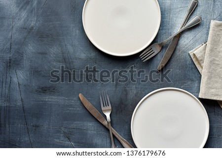 White craft plate, cutlery and napkin on dark stone table. Top view, copy space, Table setting. background for menu, layout, place for text , recipe background 