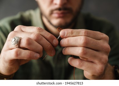 White Craftsman Holding Sewing Needle With Thread While Working In Workshop