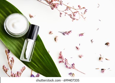 White cream bottle placed, Blank label package for mock up on a green foliage background and flowers. The concept of natural beauty products.