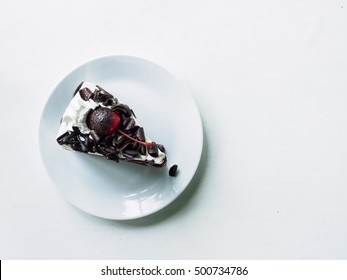 White Cream, Cheery And Chocolate Of Face Cake Slice On Plate Of White Desk Background, Top View And Copy Space