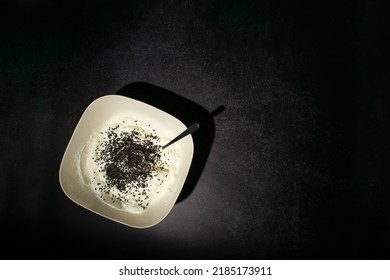 White Cream Filling With Chocolate Sprinkles Whisked In A Bowl On Black Background. Black And White Aesthetic Flat Lay.  Playing With Light And Shadow. Process Of Making Birthday Cheesecake.