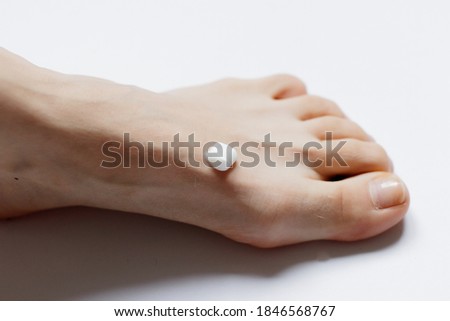 White cream on a woman's leg on a white background .Woman at home spa creaming her feet close up photo