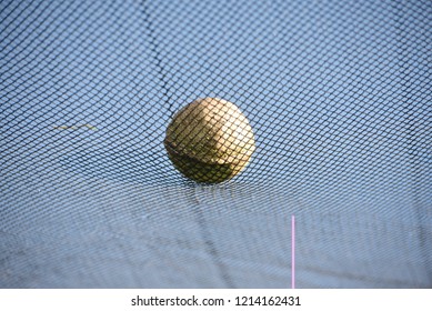 A white cricket ball on top of a nylon nets unique blurry photo