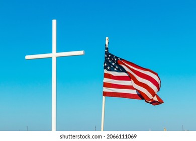 White Cross And American Flag Against Blue Sky Background