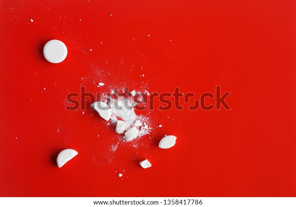 White crushed and broken tablets pills on red\
background. Copy space
