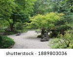 A white crushed stone path through a tree filled garden with varying shades of green foliage in Janesville, Wisconsin, USA