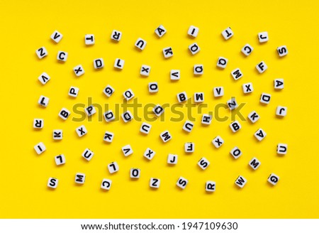 White cubes with letters scattered randomly on a yellow background. The Image can be used for many purposes, book covers or concepts relating to grammar and typography.