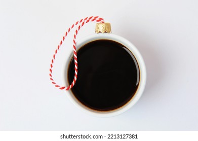 White cup of black espresso coffee decorated as Christmas ball on a red and white ribbon. Close-up, white background. New Year holiday concept - Powered by Shutterstock