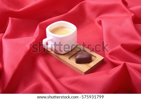 White cup of coffee and cognac in a glass, pralines on red background.