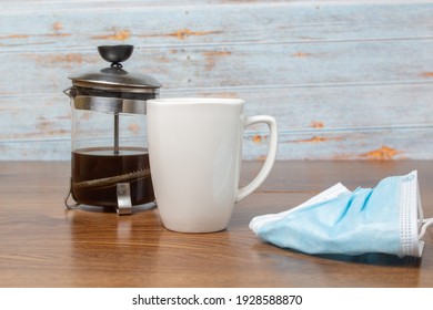 White Cup Of Coffee And French Press With Coffee Next To Facial Mascara For New Normal On Wooden Boards