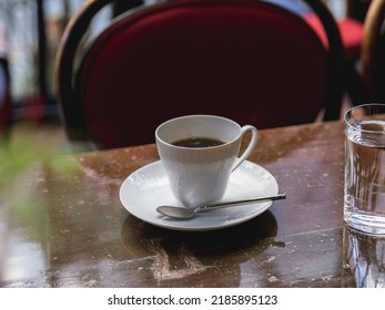 Une tasse de café blanc dans un café à la française, servi avec un verre d'eau.