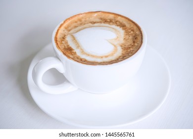White Cup of coffee with milk foam so delicious on white wooden table texture.