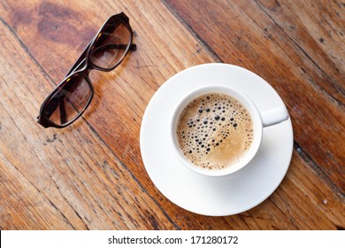 A cup of coffee next to a pair of glasses photo – Free Italy Image