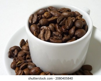 Photo of White cup of coffee (taza de café) full of fresh roasted coffee beans (granos de café) ready to be prepared. 