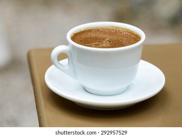 White Cup With Frothy Greek Coffee On A Cafe Table