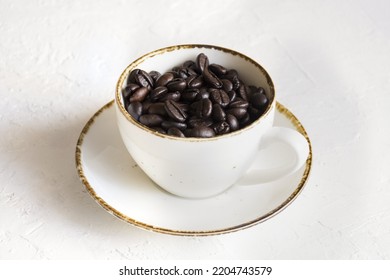 A white cup full of coffee beans  Representing a cup of dark coffee 