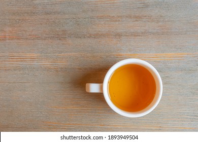 A White Cup Of Green Tea Stands On A Light Table. Top View, Copy Space