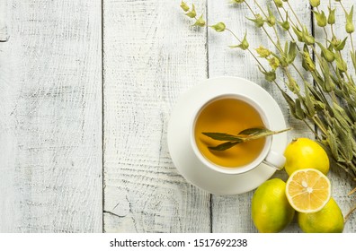 White Cup Of Herbal Sage Tea With Dried Sage Leaves And Lemon On White Wooden Rustic Background. Herbal Tea Hot Drink Concept,  Salvia Officinalis