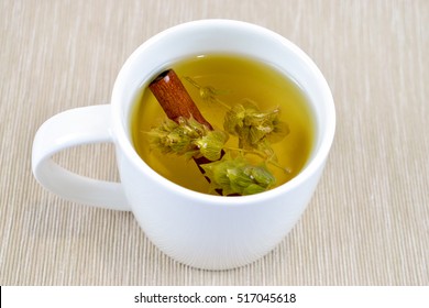 White cup of herbal tea - sage tea & cinnamon stick