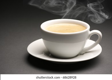 White Cup Of Hot Coffee With Steam On Dark Gray Background.
