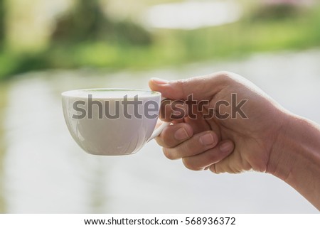 Similar – Foto Bild Frau Hand, die eine Tasse Kaffee von einem Holztisch im Garten aufzieht.