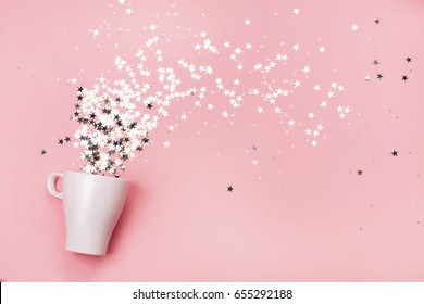 White Cup Jug With Little Star-shaped Sparkles, Pouring Out Of It. Flat Lay.