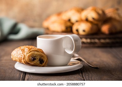 White Cup Of Tea With Mini Chocolate Bun, Puff Pastry On Old Wooden Table. Tasty Tea Break Concept, Copy Space.