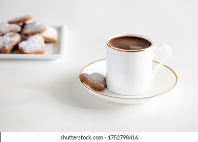 A white cup of traditional Turkish coffee with heart shaped cookies isolated on white Close up view - Powered by Shutterstock