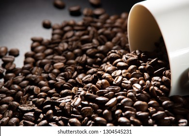 white cups with a pattern and grains of coffee on a black background