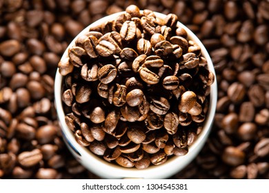 white cups with a pattern and grains of coffee on a black background