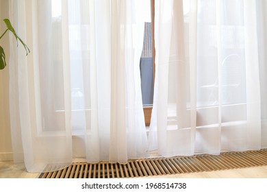 A white curtain flies in the wind. Ventilation and floor heating near the balcony. Insulation in the floor.