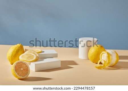White cylinder podiums for display cosmetic product of lemon extract, fresh lemon and lemon slices decorated on blue background. Photo for advertising, blank space to placed your design