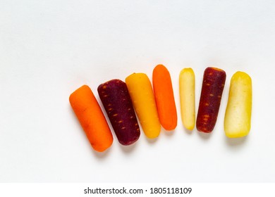 White, Dark, Yellow And Orange Pilled Baby Cut Carrots Lined On White Background