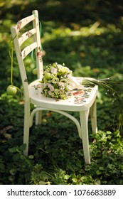 White Decoupage Chair With Green Bridal Bouquet. Green Grass At The Apple Garden, Wedding Ceremony. Summer Wedding. Soft Blur Bokeh, Design Template Card.