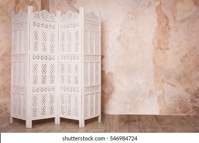 White Delicate Decorative Wood Panel On Brown Plaster Wall. Boudoir Wedding Room. Retro Folding Screen. Vintage Ornate Carved Folding Screen. 