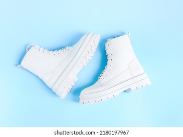 White demi-season martens boots made of eco-leather with a rough sole lie in the center on a light blue background, flat lay close-up. The concept of women's shoes.