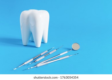 White dental tooth model with dentistry tools for teeth dental care on blue background. Oral dental hygiene concept. Copy space.