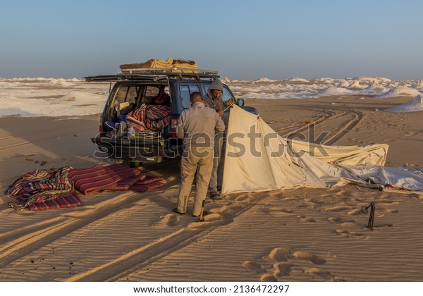 WHITE DESERT, EGYPT - FEBRUARY 6,\
2019: Tour guides setting up a tent in the White Desert,\
Egypt